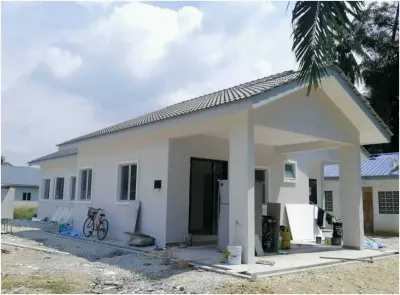 Banglo setingkat RumahHQ pada peringkat hampir siap — dinding putih sudah dicat, bumbung genting kelabu lengkap, porch kereta berbumbung, tingkap aluminium dipasang, dengan baldi cat dan bahan kemasan masih di tapak